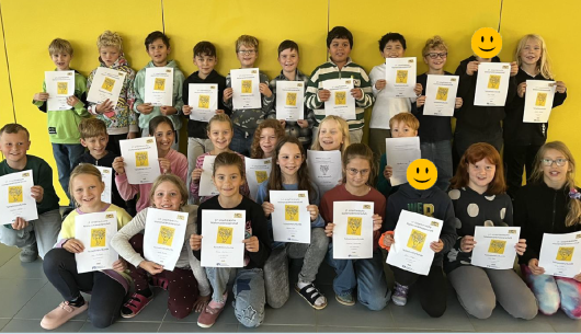 Fröhliche Kinder halten Urkunde der Mathemeisterschaft in den Händen